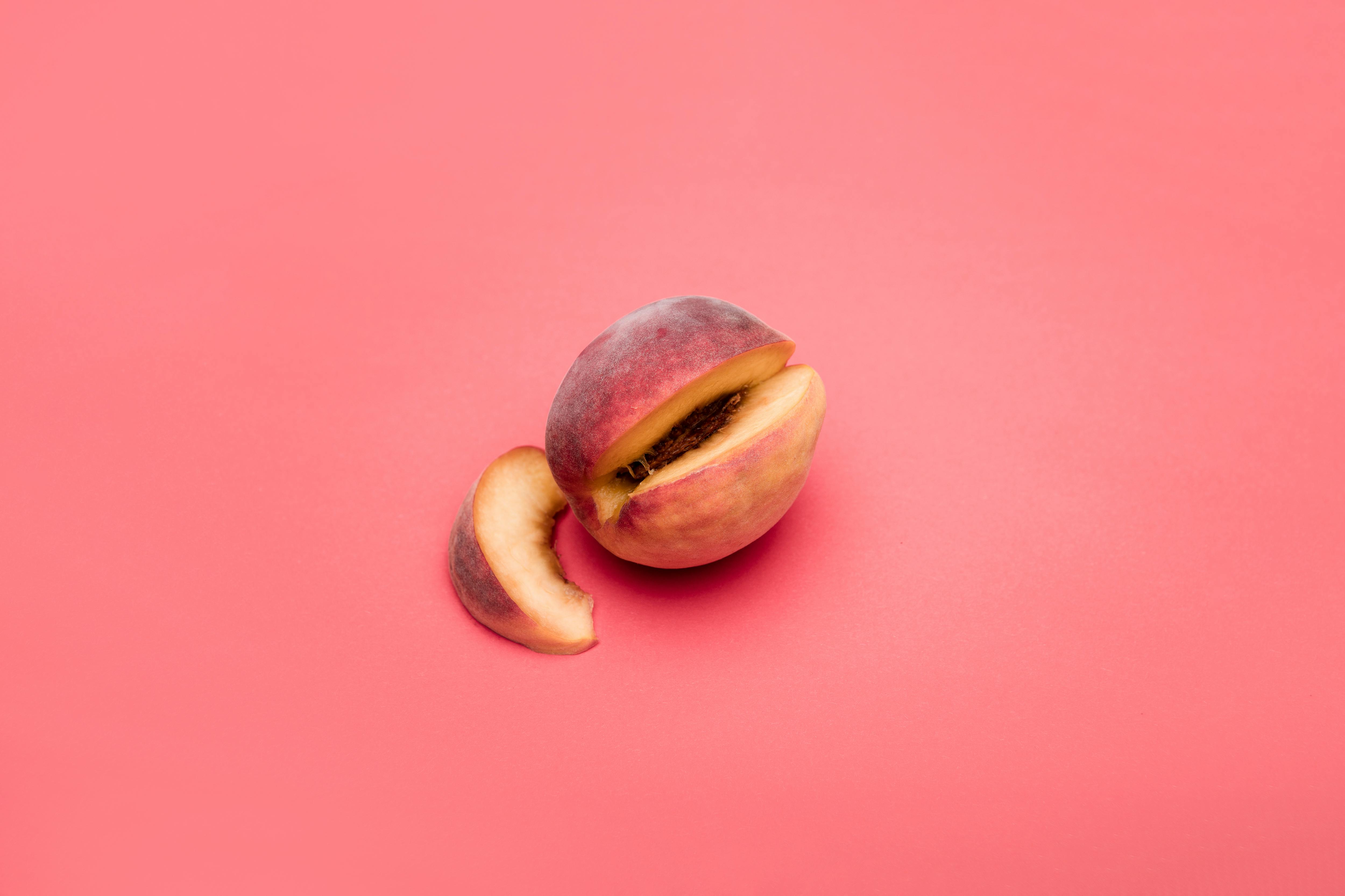 Cut peach and slices on a pink background showing vibrant summer freshness.